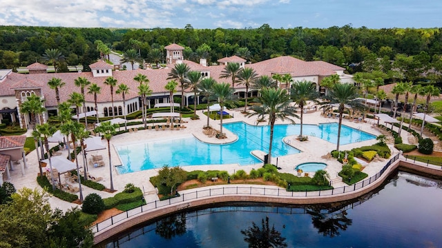 community pool featuring a wooded view and a patio
