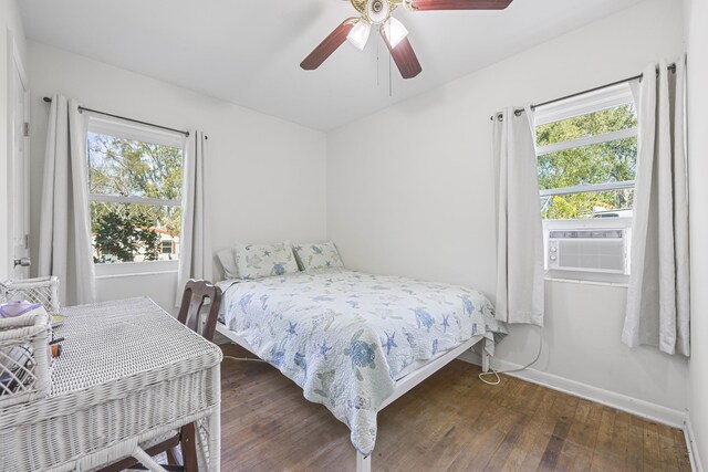 bedroom with multiple windows, cooling unit, baseboards, and wood-type flooring