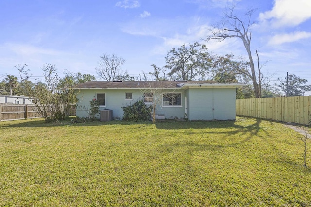 back of house featuring concrete block siding, a yard, and a fenced backyard