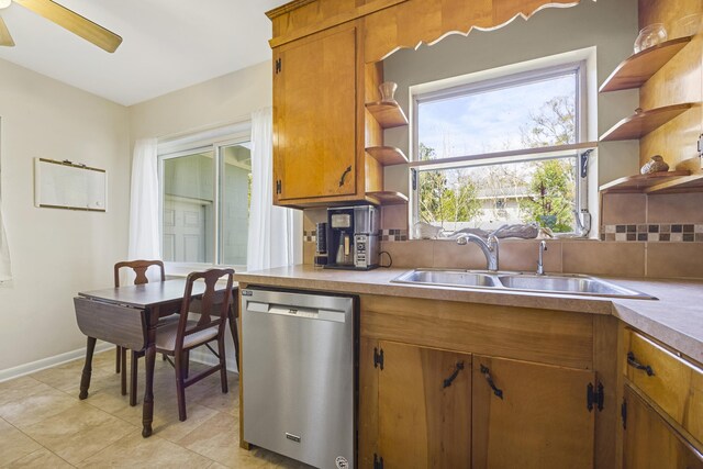 kitchen with tasteful backsplash, open shelves, brown cabinets, stainless steel dishwasher, and a sink