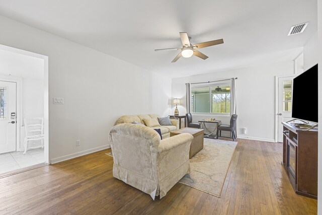 living room featuring visible vents, wood-type flooring, baseboards, and ceiling fan