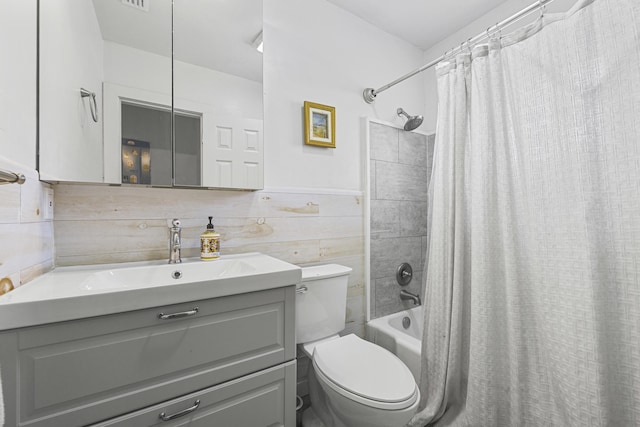 full bathroom with vanity, a wainscoted wall, shower / tub combo, tile walls, and toilet