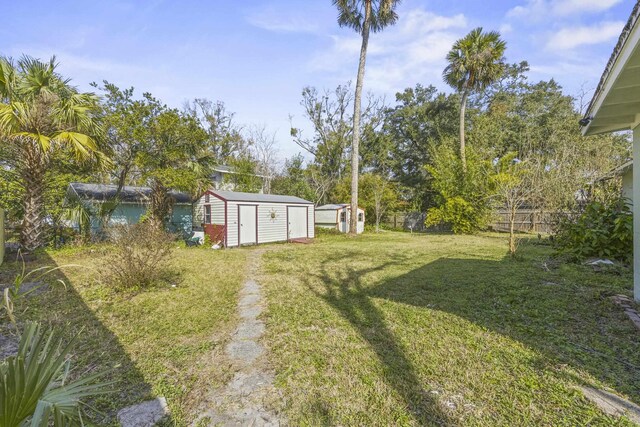 view of yard featuring a storage shed, an outbuilding, and fence