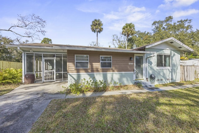 view of front of home featuring fence, a front yard, and a sunroom