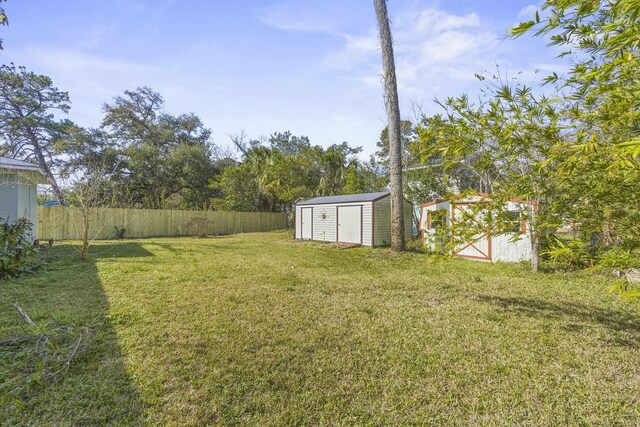 view of yard with a storage shed, fence, and an outbuilding