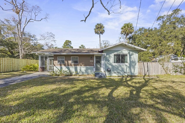 view of front of house featuring entry steps, a front yard, fence, and a sunroom