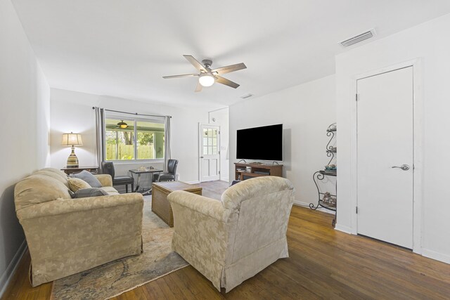 living area featuring visible vents, baseboards, dark wood-type flooring, and ceiling fan