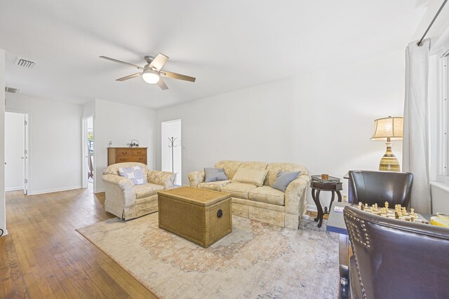 living area featuring ceiling fan, visible vents, baseboards, and hardwood / wood-style floors