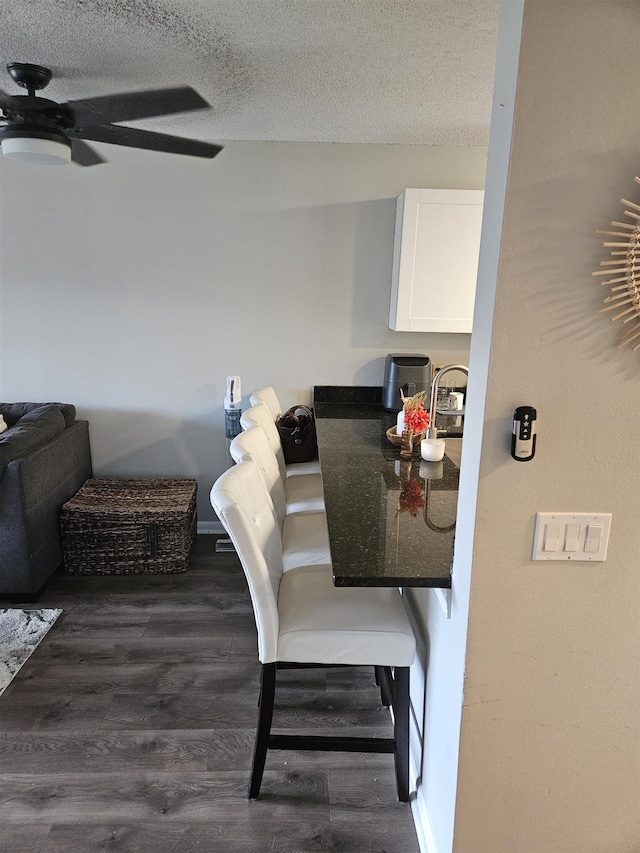 dining room featuring ceiling fan, dark wood-type flooring, and a textured ceiling