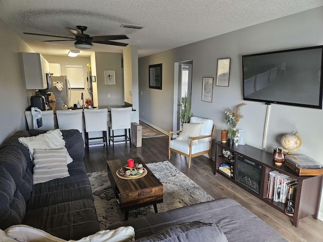 living room featuring ceiling fan, a textured ceiling, and hardwood / wood-style flooring