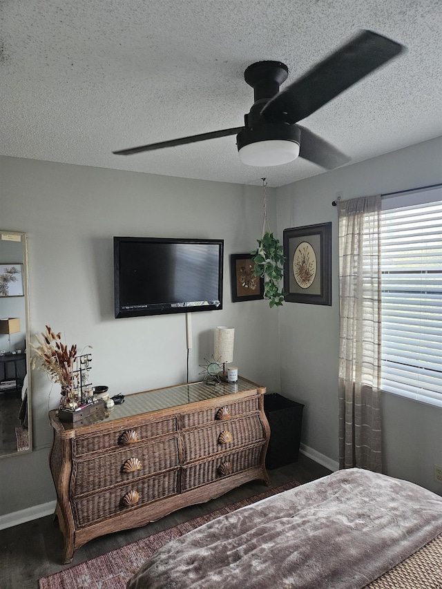 bedroom with a textured ceiling, ceiling fan, and dark wood-type flooring