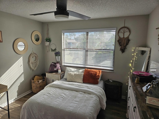 bedroom with a textured ceiling, ceiling fan, and dark wood-type flooring