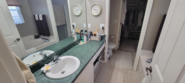 bathroom with tile patterned flooring, vanity, toilet, and a tub to relax in