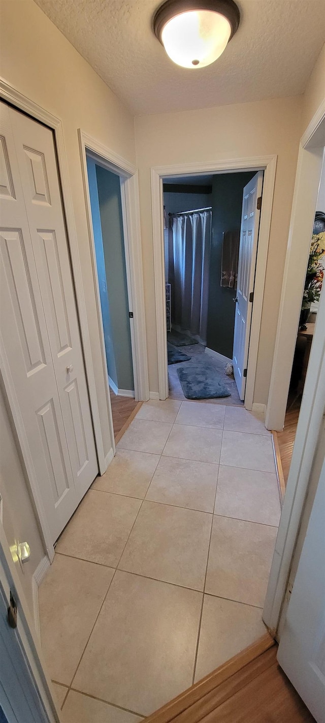 corridor featuring light tile patterned floors and a textured ceiling