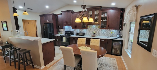 kitchen featuring pendant lighting, a breakfast bar, black appliances, and lofted ceiling