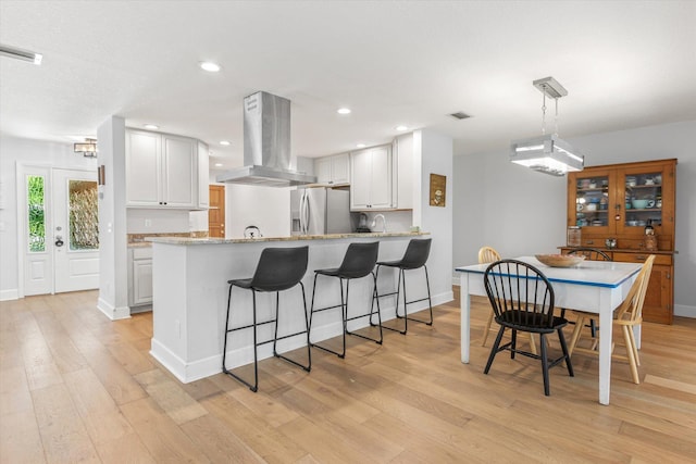 200 Raintree Trl, Saint Augustine, FL 32086 - kitchen with wall chimney exhaust hood, stainless steel fridge with ice dispenser, white cabinetry, a peninsula, and light wood-style flooring