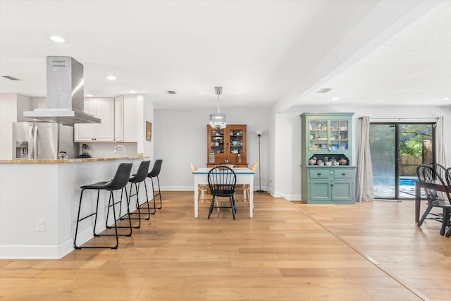 200 Raintree Trl, Saint Augustine, FL 32086 - kitchen featuring stainless steel refrigerator with ice dispenser, island exhaust hood, light wood finished floors, white cabinetry, and a kitchen bar