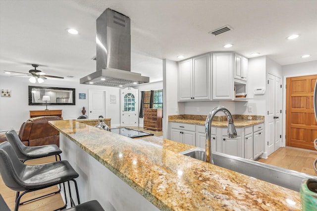 200 Raintree Trl, Saint Augustine, FL 32086 - kitchen featuring extractor fan, electric stovetop, ceiling fan, light stone countertops, and a breakfast bar