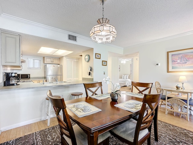 dining space with ceiling fan, sink, crown molding, hardwood / wood-style floors, and a textured ceiling