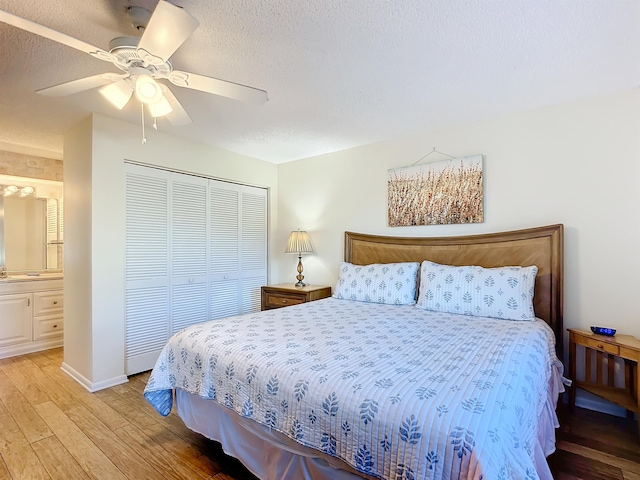 bedroom featuring ensuite bath, ceiling fan, a textured ceiling, a closet, and light wood-type flooring