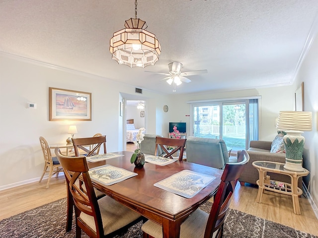 dining area featuring hardwood / wood-style flooring, ceiling fan, crown molding, and a textured ceiling