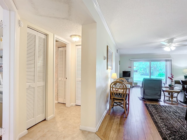 corridor with crown molding, light hardwood / wood-style flooring, and a textured ceiling