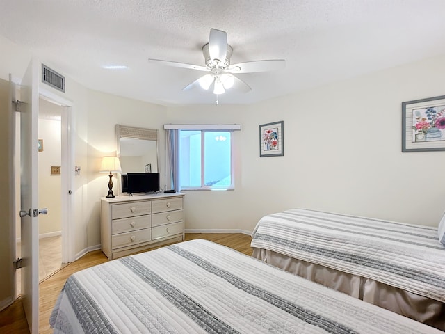 bedroom with ceiling fan, light hardwood / wood-style floors, and a textured ceiling