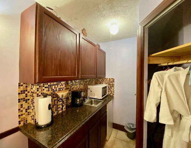 interior space with sink, a textured ceiling, and light tile patterned floors