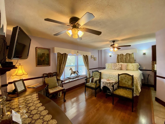 bedroom featuring ceiling fan, hardwood / wood-style floors, and a textured ceiling