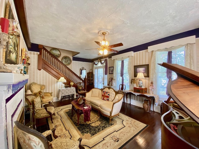 living room featuring ceiling fan, dark wood-type flooring, and a textured ceiling