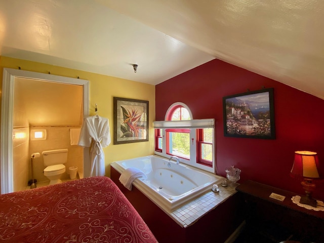 bathroom featuring toilet, a tub to relax in, and vaulted ceiling