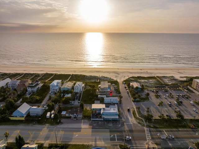 aerial view at dusk with a view of the beach and a water view