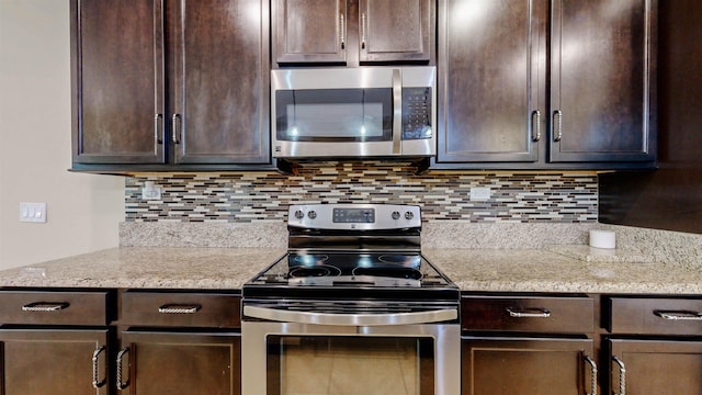 61 Grey Hawk Dr, Saint Augustine, FL 32092 - kitchen with stainless steel appliances, dark brown cabinetry, tasteful backsplash, and light stone counters