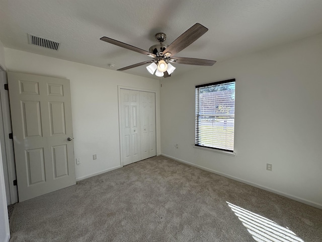 unfurnished bedroom with ceiling fan, a closet, and light carpet