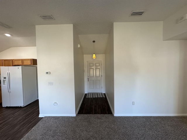 kitchen with pendant lighting, dark carpet, white fridge with ice dispenser, and vaulted ceiling