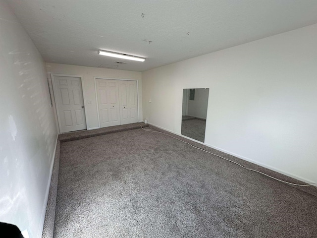 unfurnished bedroom featuring a textured ceiling, a closet, and carpet flooring