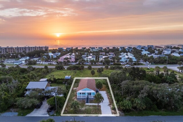 aerial view at dusk featuring a water view