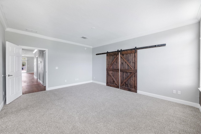 spare room featuring a barn door, carpet, and ornamental molding