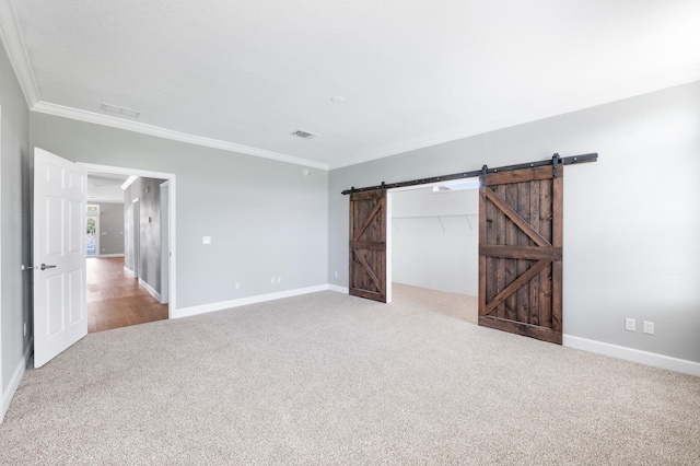 unfurnished room featuring a barn door, crown molding, and light carpet