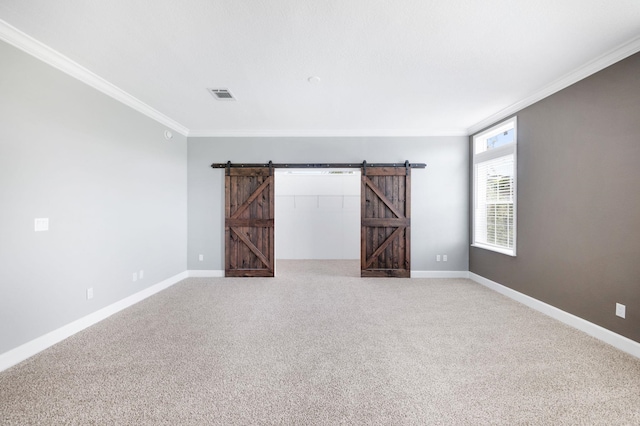 spare room featuring a barn door, crown molding, and carpet floors