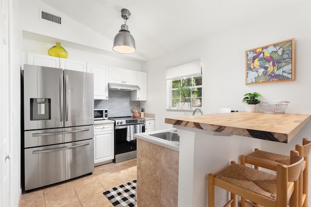 kitchen featuring a breakfast bar, butcher block countertops, pendant lighting, stainless steel appliances, and white cabinets