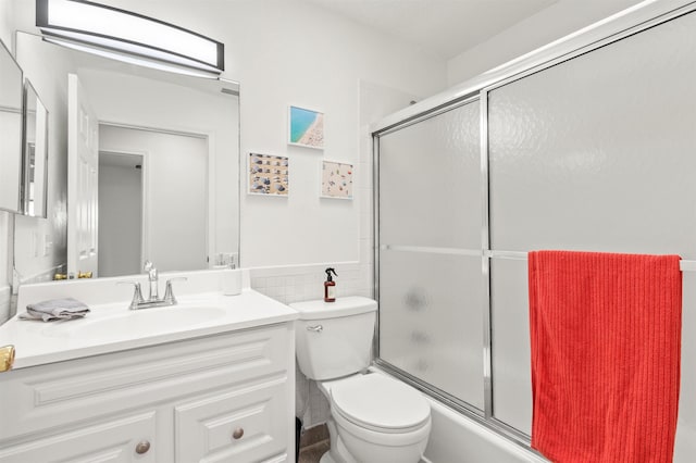 full bathroom featuring enclosed tub / shower combo, tile walls, vanity, and toilet