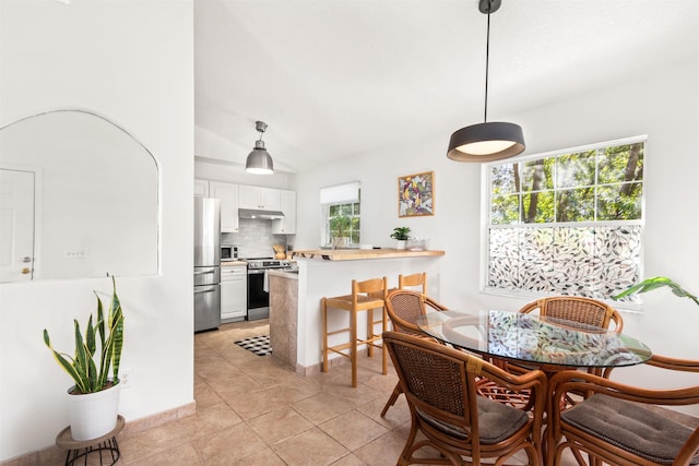 dining space with lofted ceiling, light tile patterned floors, and plenty of natural light