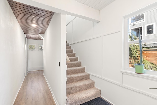 stairs featuring hardwood / wood-style flooring and wooden ceiling