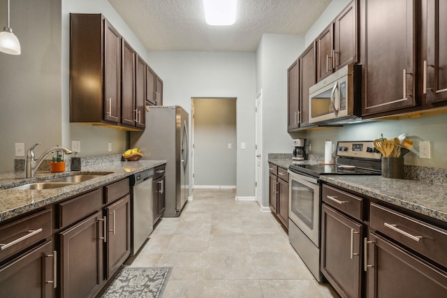 kitchen featuring sink, hanging light fixtures, stainless steel appliances, a textured ceiling, and dark brown cabinets