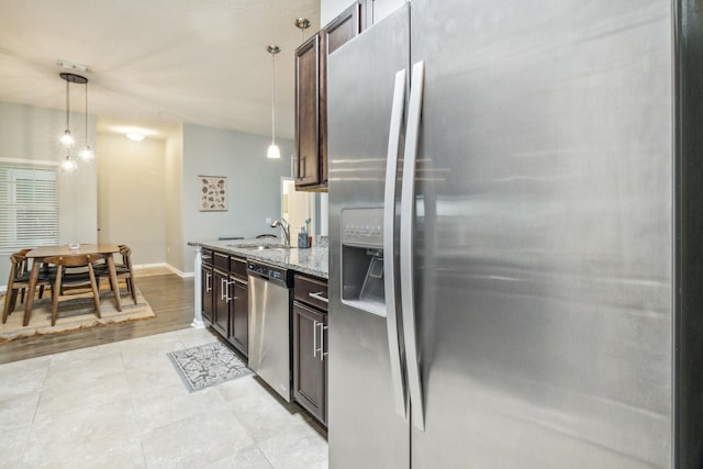 kitchen featuring light stone counters, dark brown cabinets, stainless steel appliances, light hardwood / wood-style floors, and hanging light fixtures