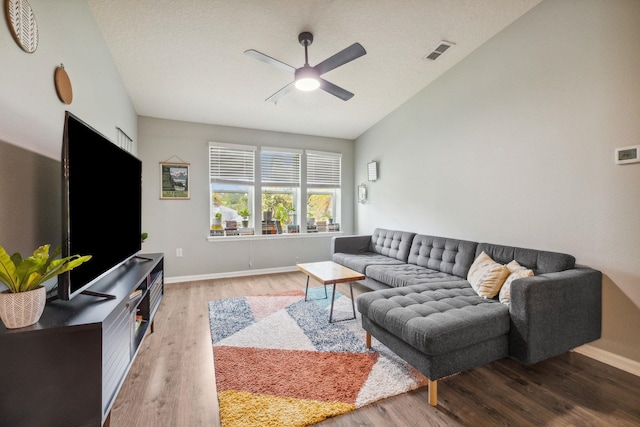 living room with hardwood / wood-style flooring, ceiling fan, a textured ceiling, and vaulted ceiling