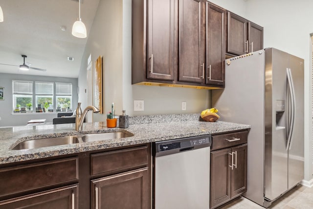 kitchen with light stone countertops, stainless steel appliances, ceiling fan, and sink