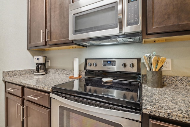 kitchen with dark brown cabinets, light stone counters, and appliances with stainless steel finishes