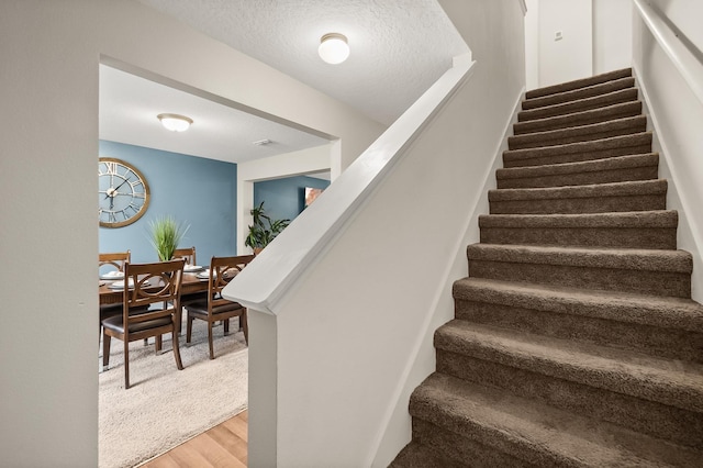 stairs featuring wood-type flooring and a textured ceiling